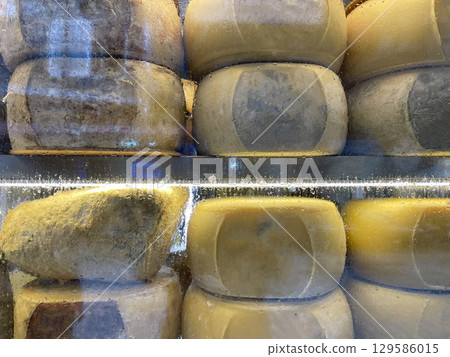Close-up of artisanal cheeses arranged on wooden shelves. Food and culinary concept 129586015