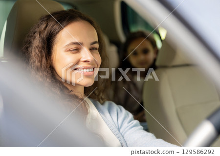 Young woman and her daughter sitting in the car and looking joyful Young woman and her daughter sitting in the car and looking joyful 129586292