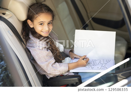 Sweet girl of school age in the car drawing and looking peaceful 129586335
