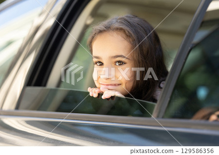 Smiling cute girl in a car window looking happy and enjoyed 129586356