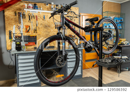 Black bike fixed for repair in organized maintenance space 129586392