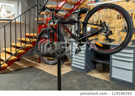 Bicycle in home garage workshop on stand surrounded by tools and equipment Bicycle in home garage workshop on stand surrounded by tools and equipment 129586393