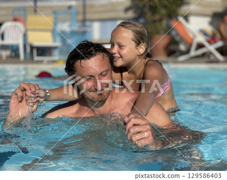 Father and Daughter Enjoying Time in the Swimming Pool 129586403