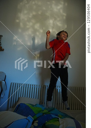 Child Joyfully Jumping on the Bed with Excitement 129586404