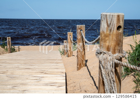 Wooden Pathway to the Beach with View of Blue Sea and Sand Dunes 129586415