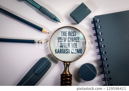 Motivational Quote Through Magnifying Glass Surrounded by Blue Stationery on White Desk 129586421