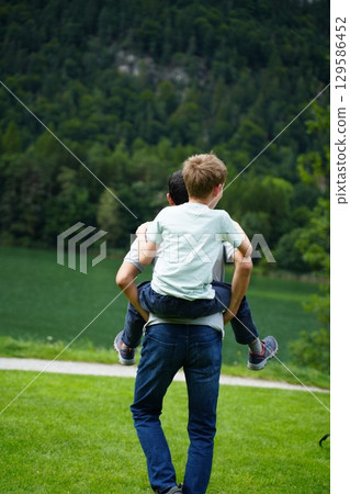 Child Piggyback Ride in Scenic Green Landscape Child Piggyback Ride in Scenic Green Landscape 129586452