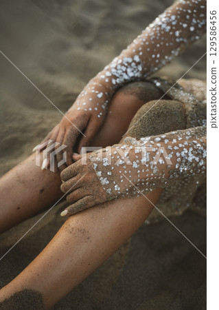 Hands with Glitter on Sandy Beach Closeup 129586456