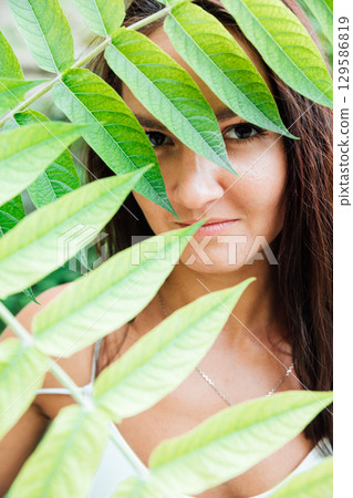 Portrait of a beautiful woman and green leaves of a plant 129586819