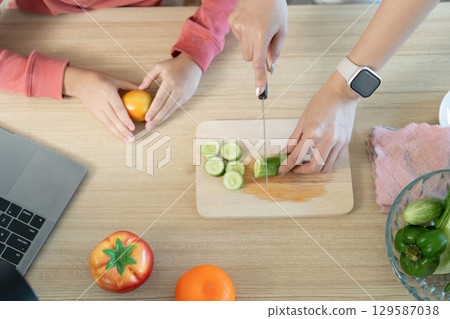 Healthy Cooking. Preparing fresh vegetables for a nutritious salad with child involvement. 129587038