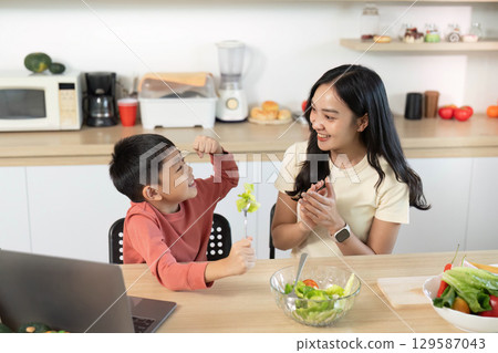 Healthy Eating. Mother and son enjoying salad preparation in modern kitchen. 129587043