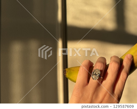 Diamond engagement ring and banana in golden afternoon light Diamond engagement ring and banana in golden afternoon light 129587609