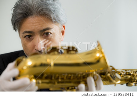 Senior man performing maintenance on a saxophone 129588411
