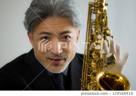 Senior man performing maintenance on a saxophone 129588419