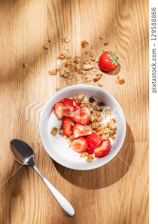 Granola or muesli with natural greek yogurt, strawberry in a bowl  on a wooden background 129588866