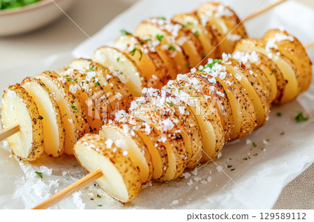 Grilled potato skewers seasoned with herbs and salt, arranged beautifully on a serving platter, showcasing delicious culinary presentation and texture 129589112