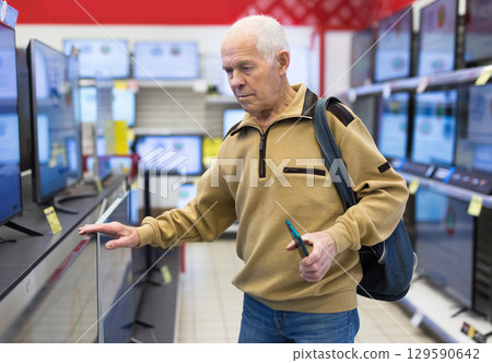elderly man choosing TV in showroom of electronics store 129590642