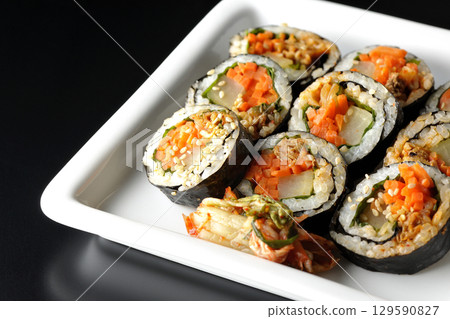 Korean-style seaweed roll kimbap photographed against a black background 129590827