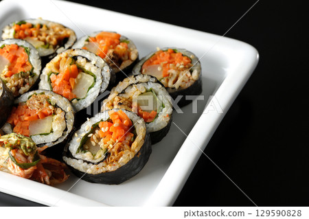 Korean-style seaweed roll kimbap photographed against a black background Korean-style seaweed roll kimbap photographed against a black background 129590828