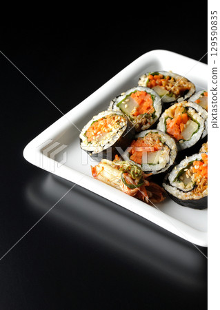 Korean-style seaweed roll kimbap photographed against a black background 129590835