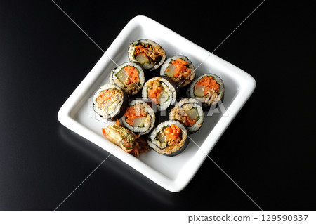 Korean-style seaweed roll kimbap photographed against a black background 129590837