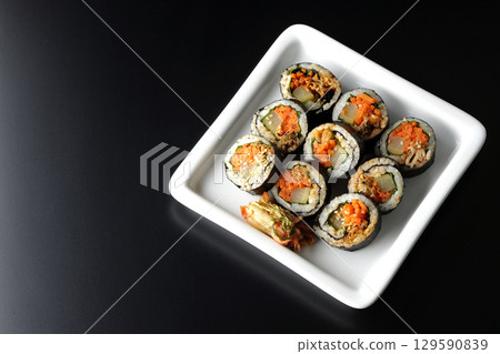 Korean-style seaweed roll kimbap photographed against a black background Korean-style seaweed roll kimbap photographed against a black background 129590839