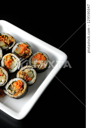 Korean-style seaweed roll kimbap photographed against a black background 129590847