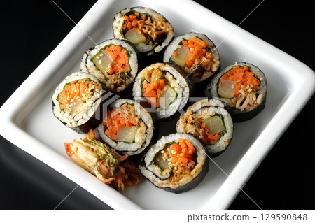 Korean-style seaweed roll kimbap photographed against a black background 129590848