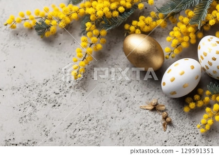 Mimosa branch, Easter eggs on gray concrete background. Beautiful Easter spring background with place for text. 129591351