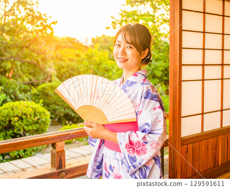 夏日傍晚,一位身穿浴衣的女子站在陽台和花園裡 夏日傍晚,一位身穿浴衣的女子站在陽台和花園裡 129591611