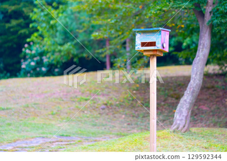 Colorful bird house hanging on a tree. Colorful bird house hanging on a tree. 129592344