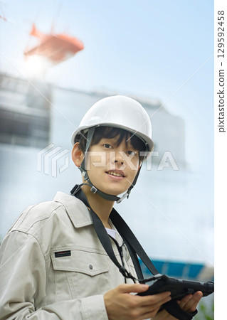 Young businessman in work clothes looking at a tablet at a construction site 129592458
