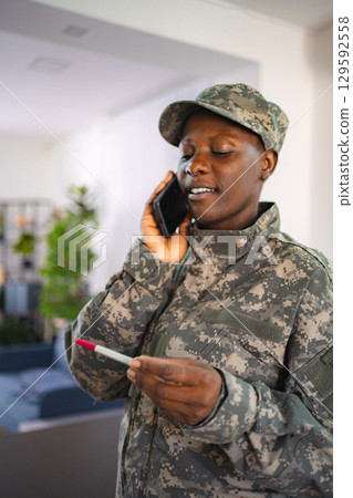 Soldier talking on the phone and holding a pregnancy test Soldier talking on the phone and holding a pregnancy test 129592558