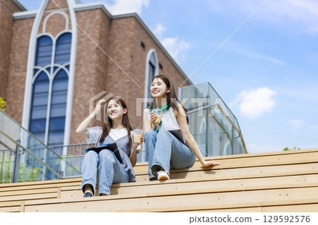 大學生和朋友坐在校園樓梯的長椅上 129592576