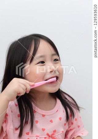 4-year-old girl in pajamas brushing her teeth 129593610