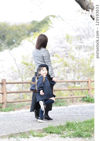 Cherry blossoms and a 3-year-old girl and her mother at the kindergarten entrance ceremony 129593633
