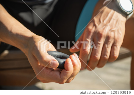 Man strengthens his grip using hand black rubber expander. He is seen holding expander with firm grip, suggesting focused exercise. Close up. 129593919