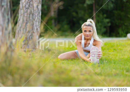 Young woman stretching outdoors in an athletic park setting Young woman stretching outdoors in an athletic park setting 129593950