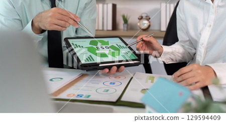 ESG Analysis Session. Professionals discussing sustainability data on a tablet. 129594409