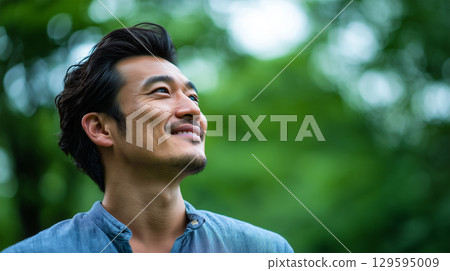 一位身穿藍色襯衫的男子仰望花園的肖像 129595009