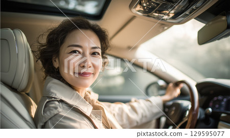 A woman sits elegantly in the driver's seat in a trench coat 129595077