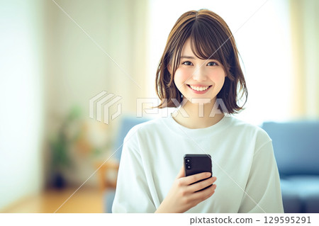 Smiling woman holding a smartphone 129595291
