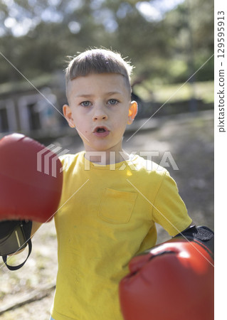 Young boxer wearing red boxing gloves practicing outdoors Young boxer wearing red boxing gloves practicing outdoors 129595913