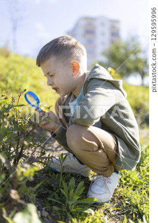 Curious child exploring nature with magnifying glass in urban park Curious child exploring nature with magnifying glass in urban park 129595996
