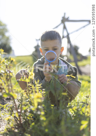 Curious child exploring nature with magnifying glass in a park Curious child exploring nature with magnifying glass in a park 129595998