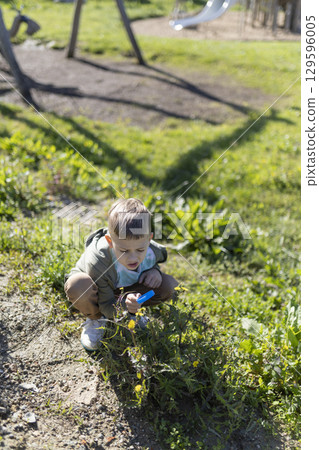 Curious child exploring nature with magnifying glass in park Curious child exploring nature with magnifying glass in park 129596005