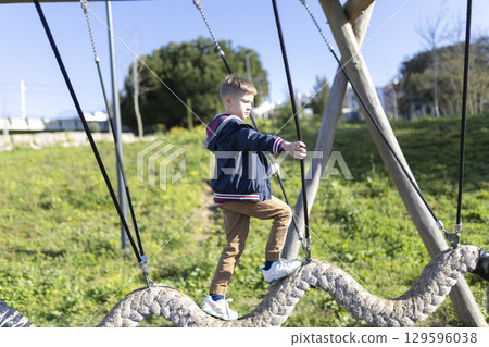 Young boy balancing on a swinging beam at the playground 129596038