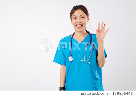 Happy friendly Asian woman nurse, clinic worker in uniform waving hi hello, a welcoming hand gesture from a smiling healthcare worker, female nurse is ready to help, isolated studio white background Happy friendly Asian woman nurse, clinic worker in uniform waving hi hello, a welcoming hand gesture from a smiling healthcare worker, female nurse is ready to help, isolated studio white background 129596448
