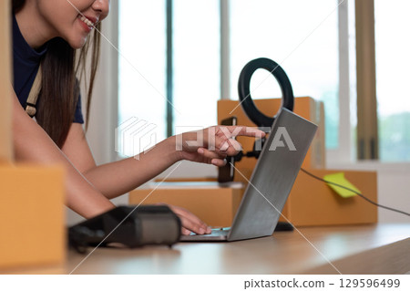 Digital Workspace. Young woman using laptop for business tasks in a home office. 129596499