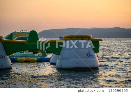 Inflatable water park with slides and obstacles on a sunny day in Makarska, Croatia Inflatable water park with slides and obstacles on a sunny day in Makarska, Croatia 129596595